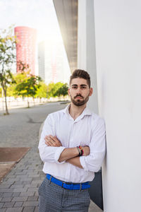 Portrait of a bearded man leaning on white wall looking aside