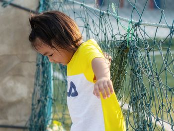 Rear view of girl looking through fence