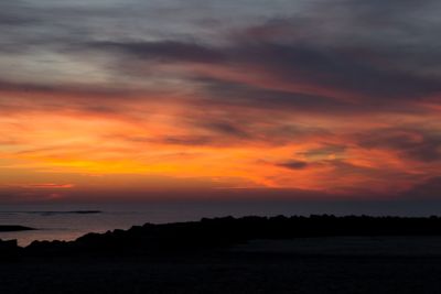 Scenic view of sea against dramatic sky during sunset