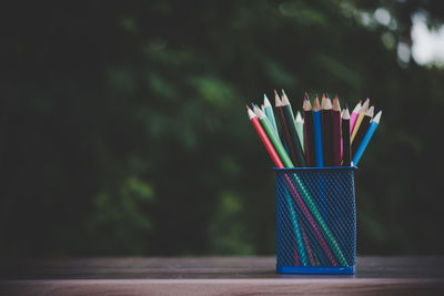 Close-up of multi colored pencils on table against wall