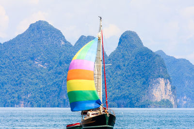 Sailboat sailing in sea against mountain