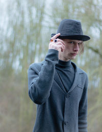 Portrait of man wearing hat while standing in forest