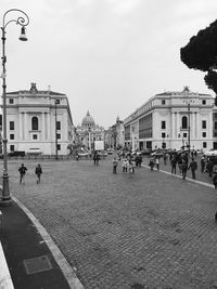 People on street against buildings in city