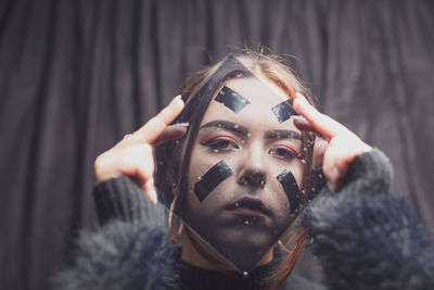 Portrait of young woman looking through glass at home