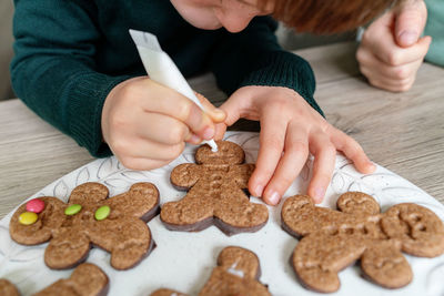 Cute boy decorating gingerbread cookies at home