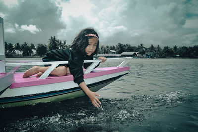 Portrait of young woman kayaking in sea against sky