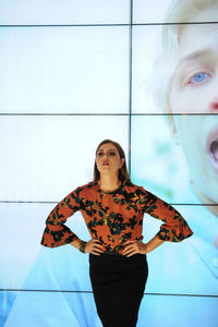 Mid adult woman posing against display screens