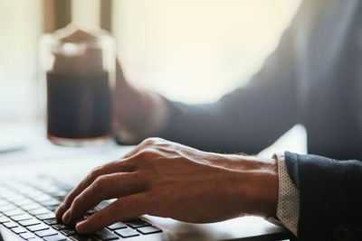 Close-up of man using laptop on table