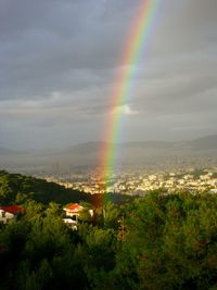 Rainbow over trees and mountains against sky