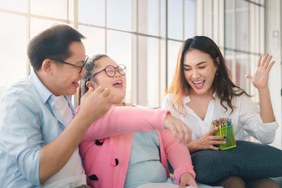 Happy friends looking away while sitting on table