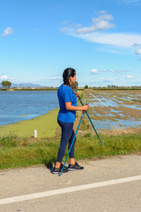 Latina woman walking with trekking poles in the ebro delta natural park, tarragona, catalonia, spain