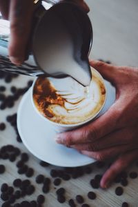 Midsection of man holding coffee cup on table