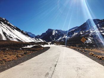 Road amidst snowcapped mountains against sky during winter