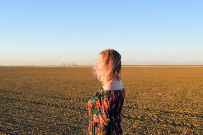 Rear view of woman standing on field against clear sky