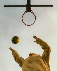 Low angle view of woman playing basketball against sky