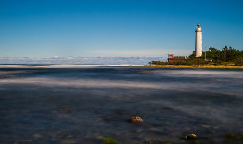 View of lighthouse at beach against clear blue sky