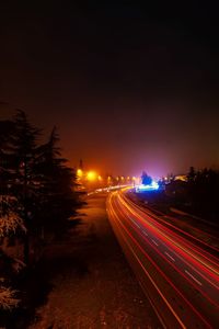 Light trails on street against sky at night