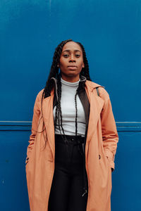 Portrait of beautiful woman standing against blue wall