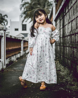 Portrait of cute girl standing on footpath