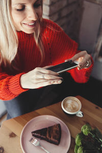 Women taking food photo on smart phone. cake mobile photography in cafe