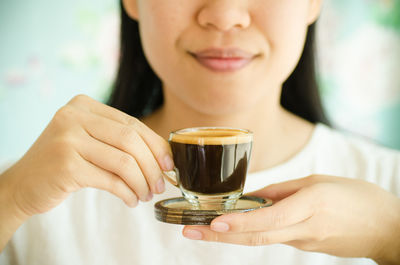 Midsection of woman holding espresso coffee cup