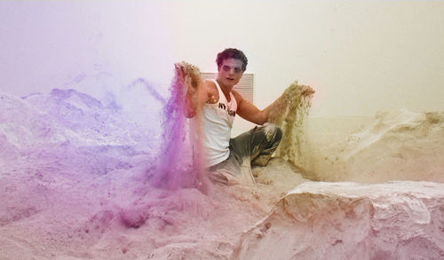 Portrait of artist sitting amidst powdered plaster at workshop