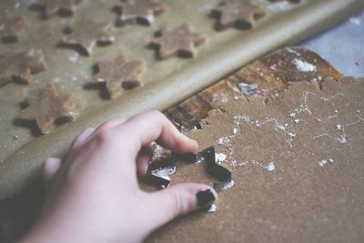 Cropped hand of woman making star shape cookie on table