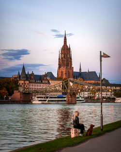 People on river by building against sky