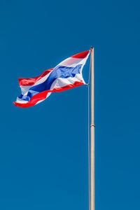 Low angle view of thai flag waving against clear blue sky