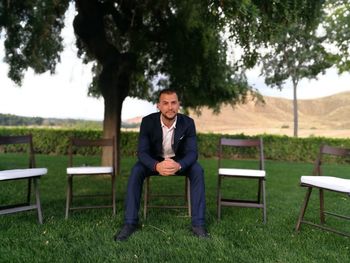 Portrait of man sitting on chair at field