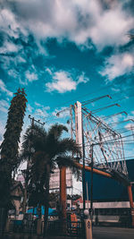 Low angle view of ferris wheel by building against sky