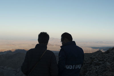 Rear view of man looking at mountains against sky