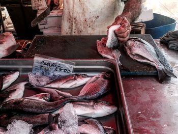 Midsection of butcher cutting fish at market