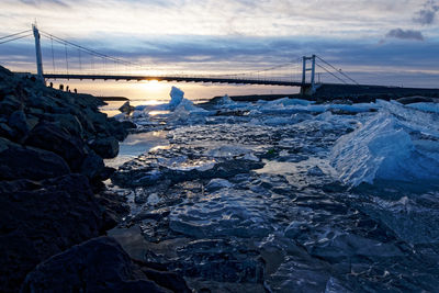 Bridge over sea against sky during sunset