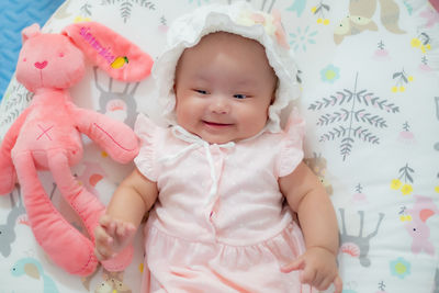 Portrait of cute baby girl lying on bed at home