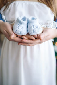 Midsection of woman holding baby booties