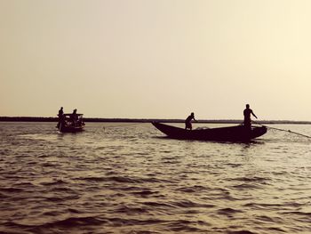 People on boat in sea against sky during sunset