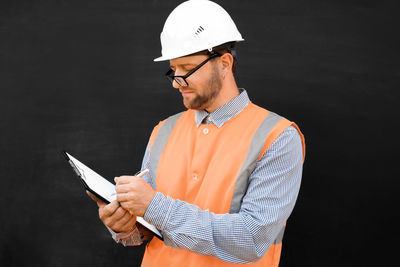 Man in white hard hats. confident build worker, black background. copy space. construction industry