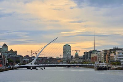 Bridge over river with buildings in background at sunset