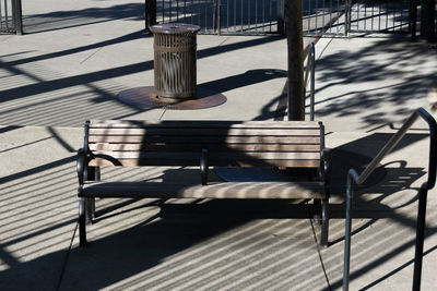 High angle view of shadow falling on empty bench at footpath