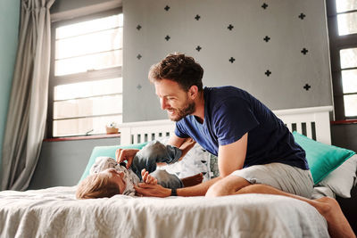 Father playing with son lying on bed