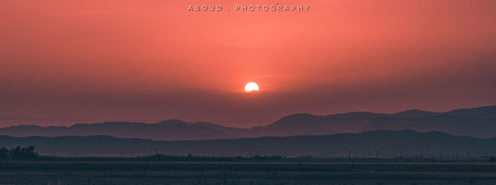 Scenic view of silhouette mountains against orange sky