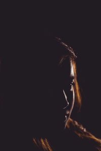 Close-up portrait of woman against black background