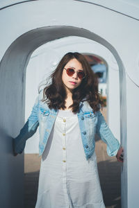 Young woman standing against wall