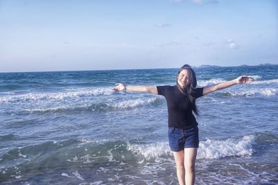 Full length of young woman at beach against sky