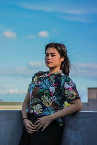 Beautiful young woman looking away against sky