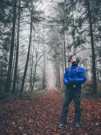 Full length of man standing by trees in forest