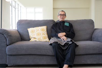 Portrait of man sitting on sofa