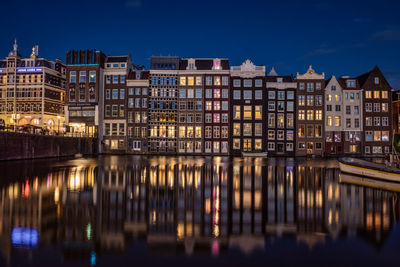 Reflection of illuminated buildings in water in amsterdam 