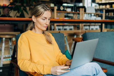 Young woman using laptop while sitting on table